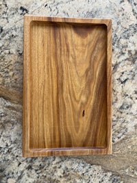 a wooden tray on top of a granite countertop